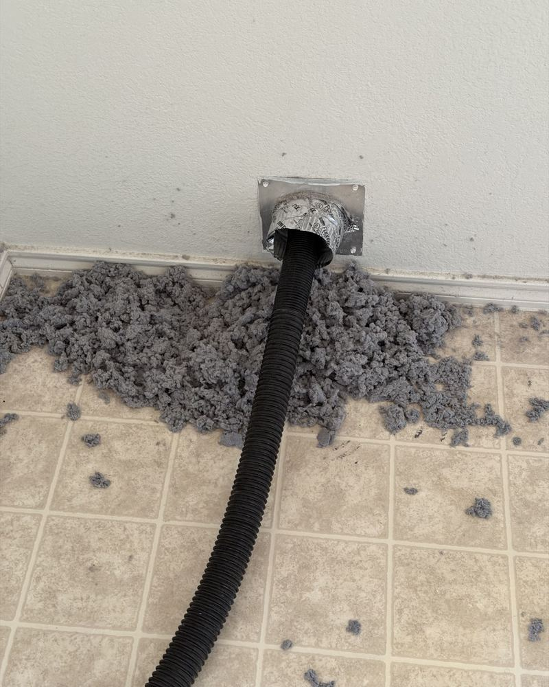 Lint pulled out of a clogged dryer vent, spread across the laundry room floor.